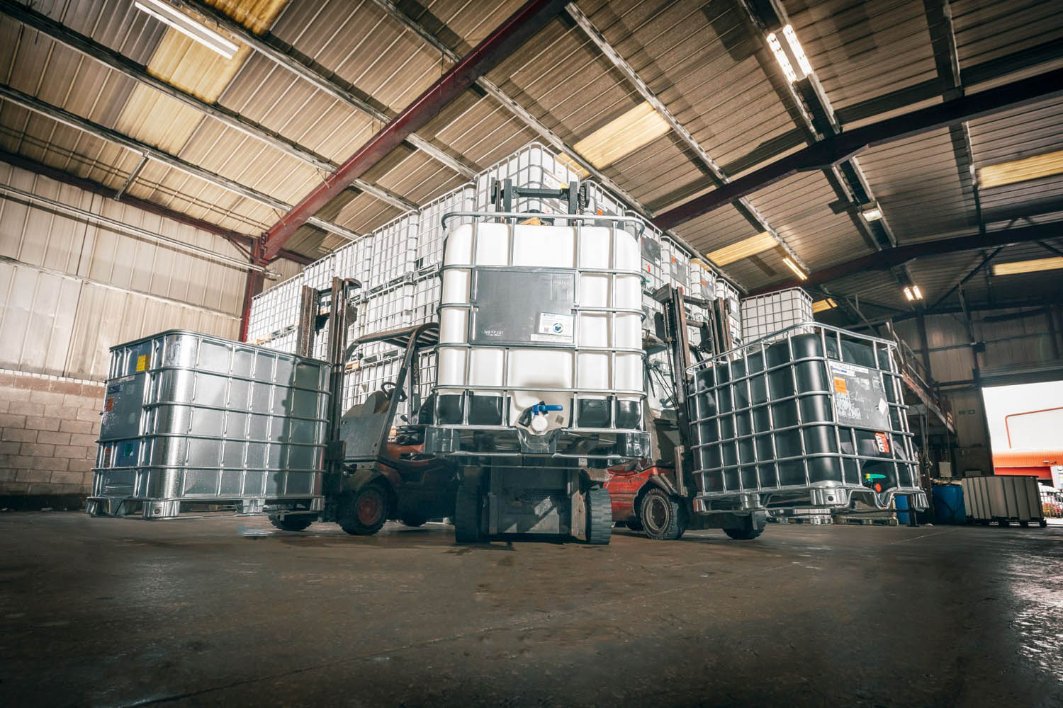 A picture of three forklifts carrying Earthed, Reconditioned and New IBCs at Recontainers Haslingden.